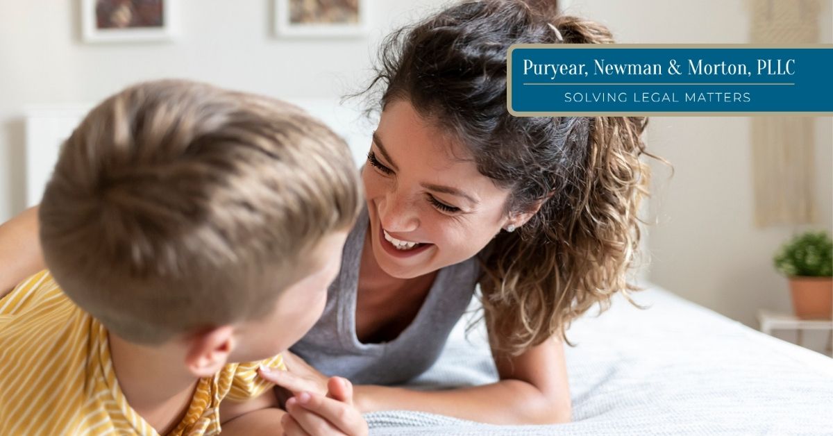 Mom with elementary-aged son laughing on a bed