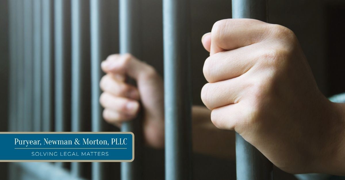 Caucasian person with both hands on jail cell bars